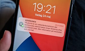 Foto på skärmen på en telefon där det har kommit ett sms om en vattenläcka från avsändare "KOMMUNEN". 