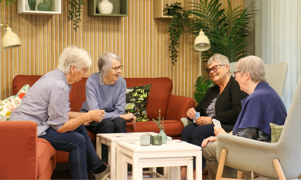 fyra damer sitter i en soffa och spelar kort
