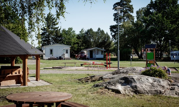 Foto på campingen med grillplatsen i förgrunden, lekplatsen och campingplatsen. 