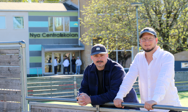 två män poserar framför grundskola