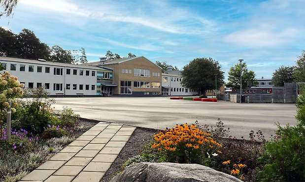 Nya Centralskolan fotograferad på sommaren med skolgården i förgrunden. 