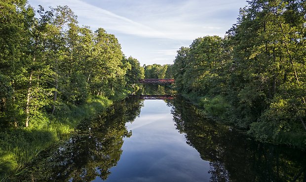 Drönarbild över en spegelblank Nossan med Brännebackabron längre bort. 