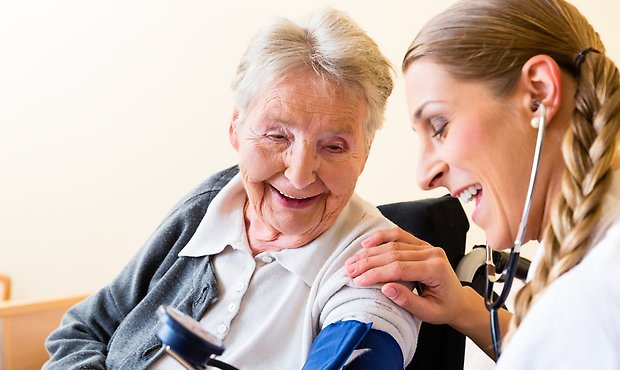 Vårdpersonal tar blodtryck på äldre person. 