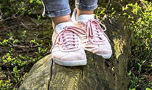 ett par fötter med rosa gympaskor som står på en sten.