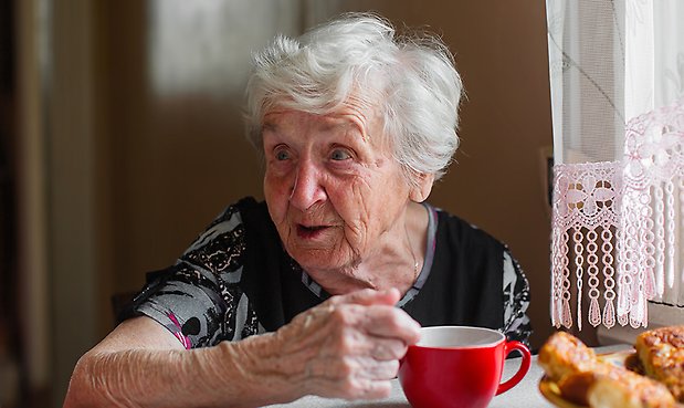 Äldre dam med en kaffekopp framför sig. 